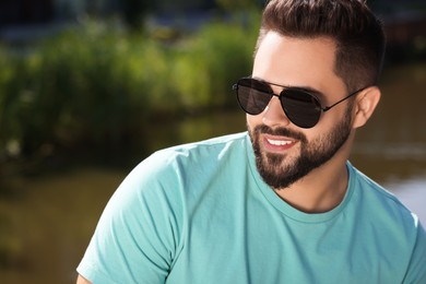 Handsome smiling man in sunglasses outdoors, space for text