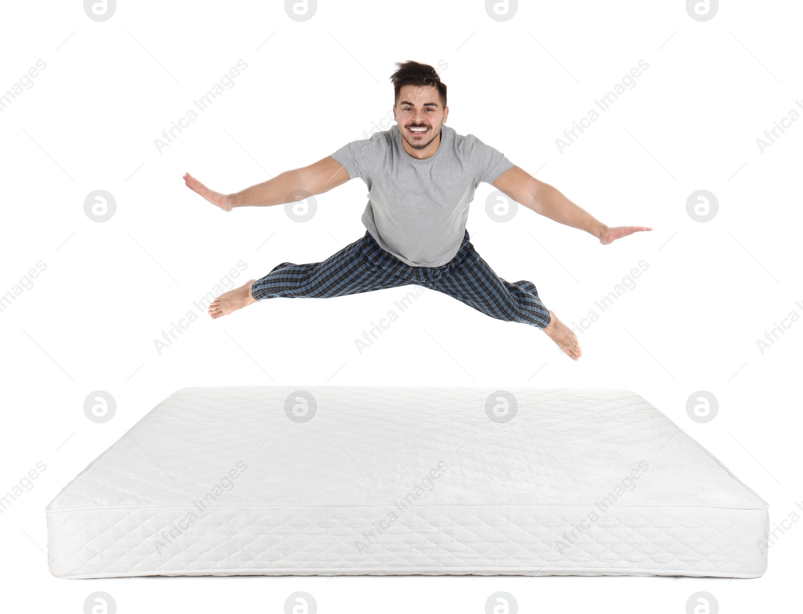 Photo of Young man jumping on mattress against white background