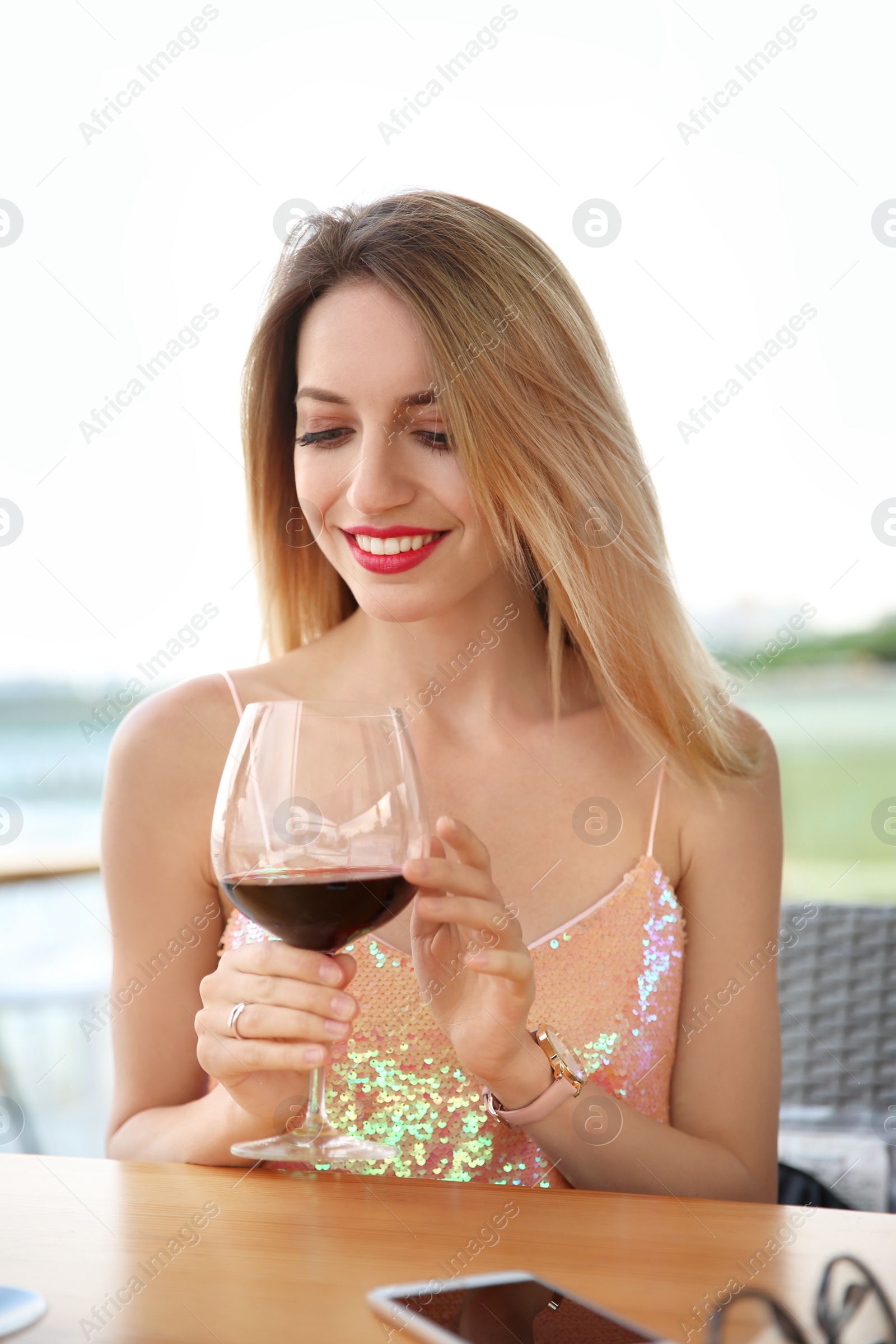 Photo of Young woman with glass of red wine at table outdoors