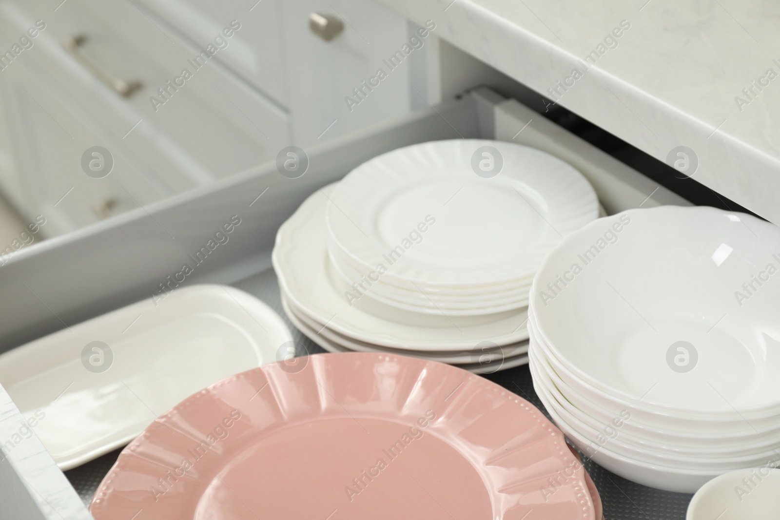 Photo of Clean plates and bowls in drawer indoors