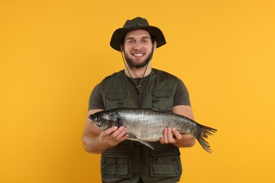 Photo of Fisherman with caught fish on yellow background