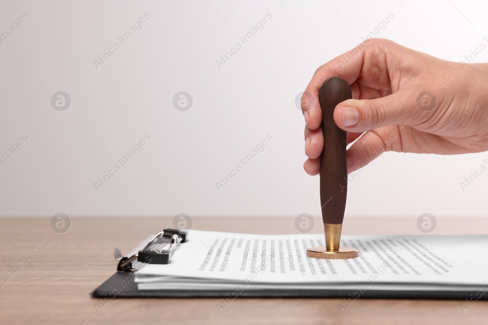 Photo of Woman stamping documents at wooden table, closeup. Space for text