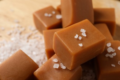 Photo of Yummy caramel candies and sea salt on table, closeup