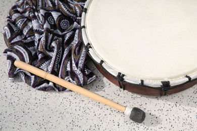 Photo of Drum and drumstick on grey table, above view. Percussion musical instrument