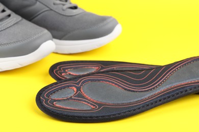 Pair of orthopedic insoles on yellow background, closeup