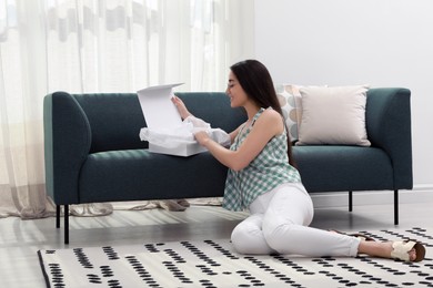 Happy young woman opening parcel at home. Internet shopping