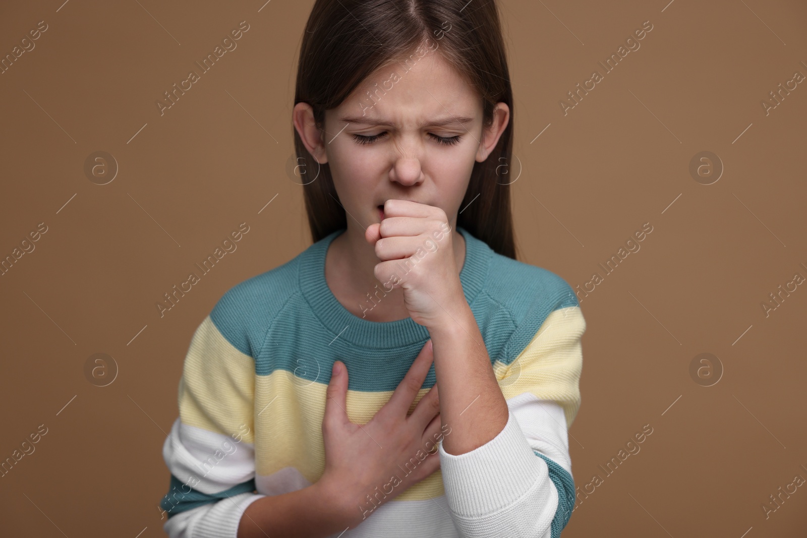 Photo of Sick girl coughing on brown background. Cold symptoms