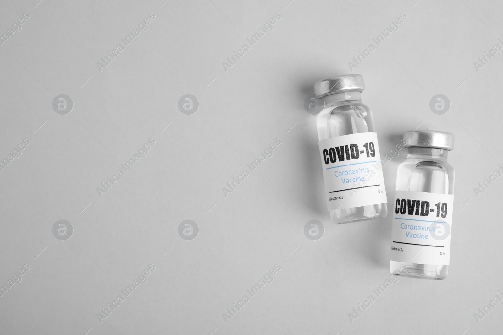 Photo of Vials with coronavirus vaccine on light background, flat lay. Space for text