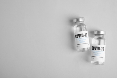 Vials with coronavirus vaccine on light background, flat lay. Space for text