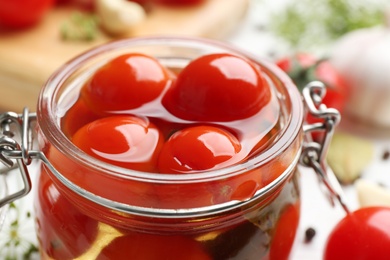 Photo of Glass jar of pickled cherry tomatoes, closeup