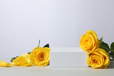 Beautiful presentation for product. Square podium and yellow roses on white table, space for text
