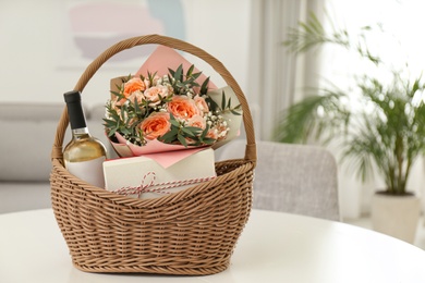 Photo of Wicker basket with gifts on table indoors. Space for text