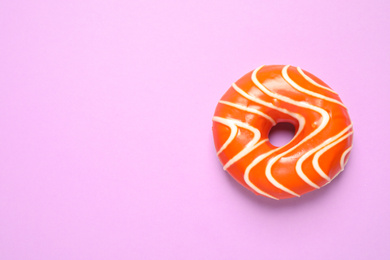 Photo of Delicious glazed donut on lilac background, top view. Space for text