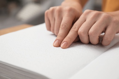 Blind woman reading book written in Braille, closeup