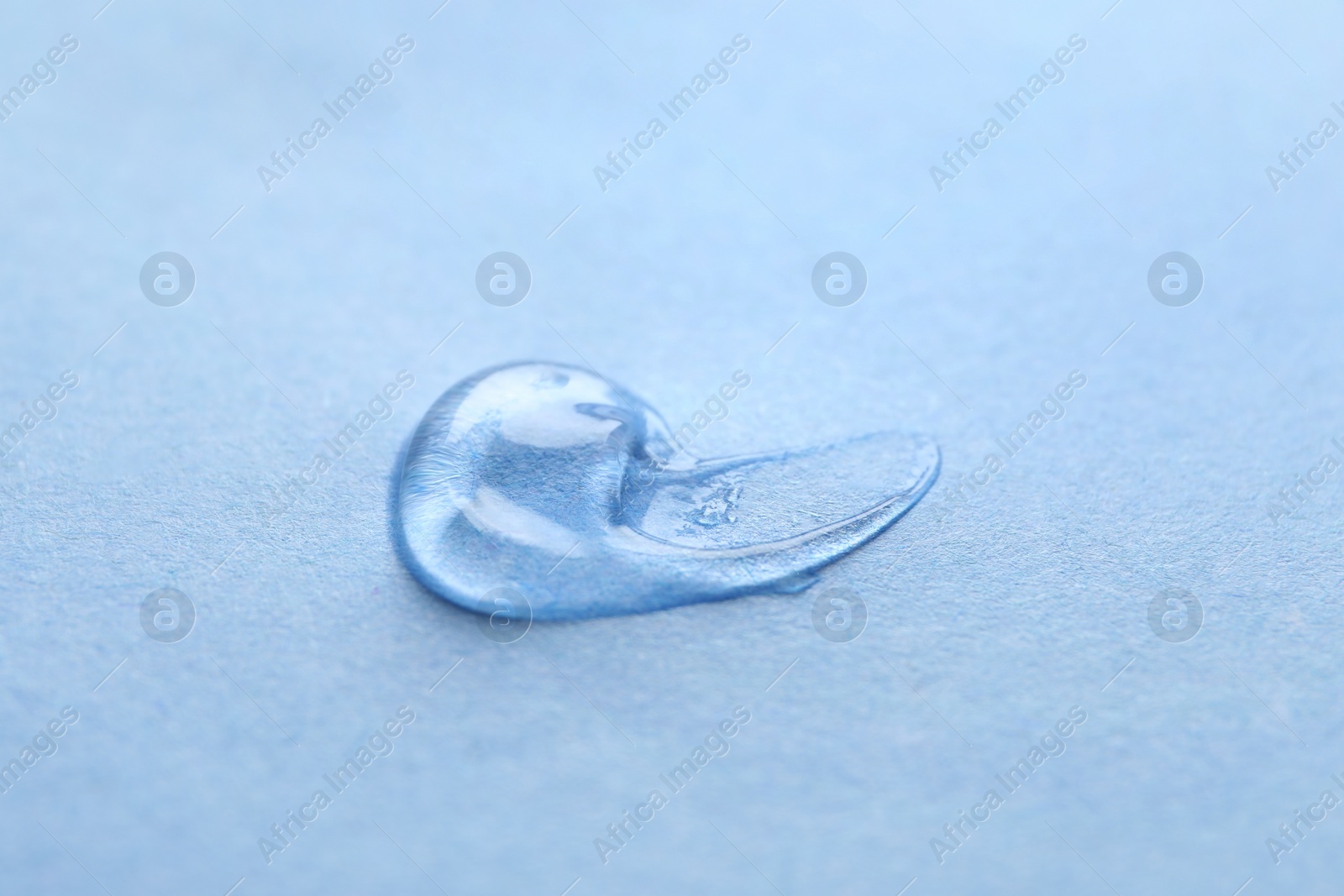 Photo of Sample of transparent gel on light blue background, closeup