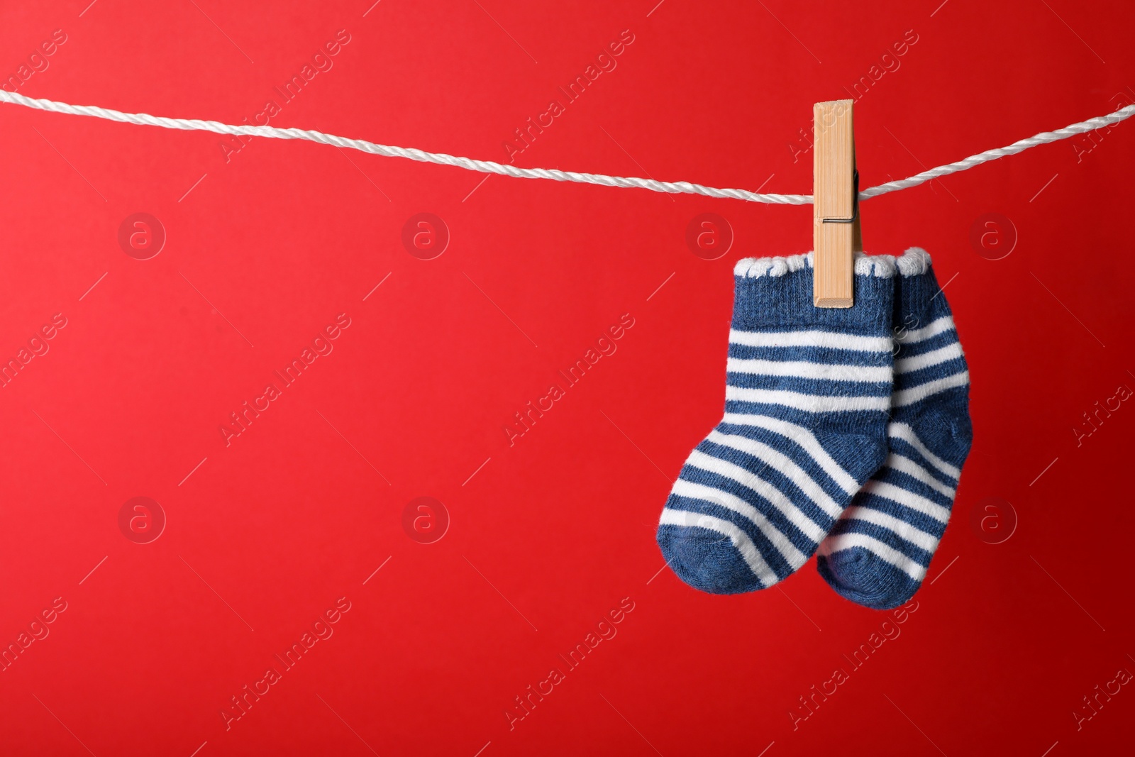 Photo of Cute child socks on laundry line against color background. Space for text