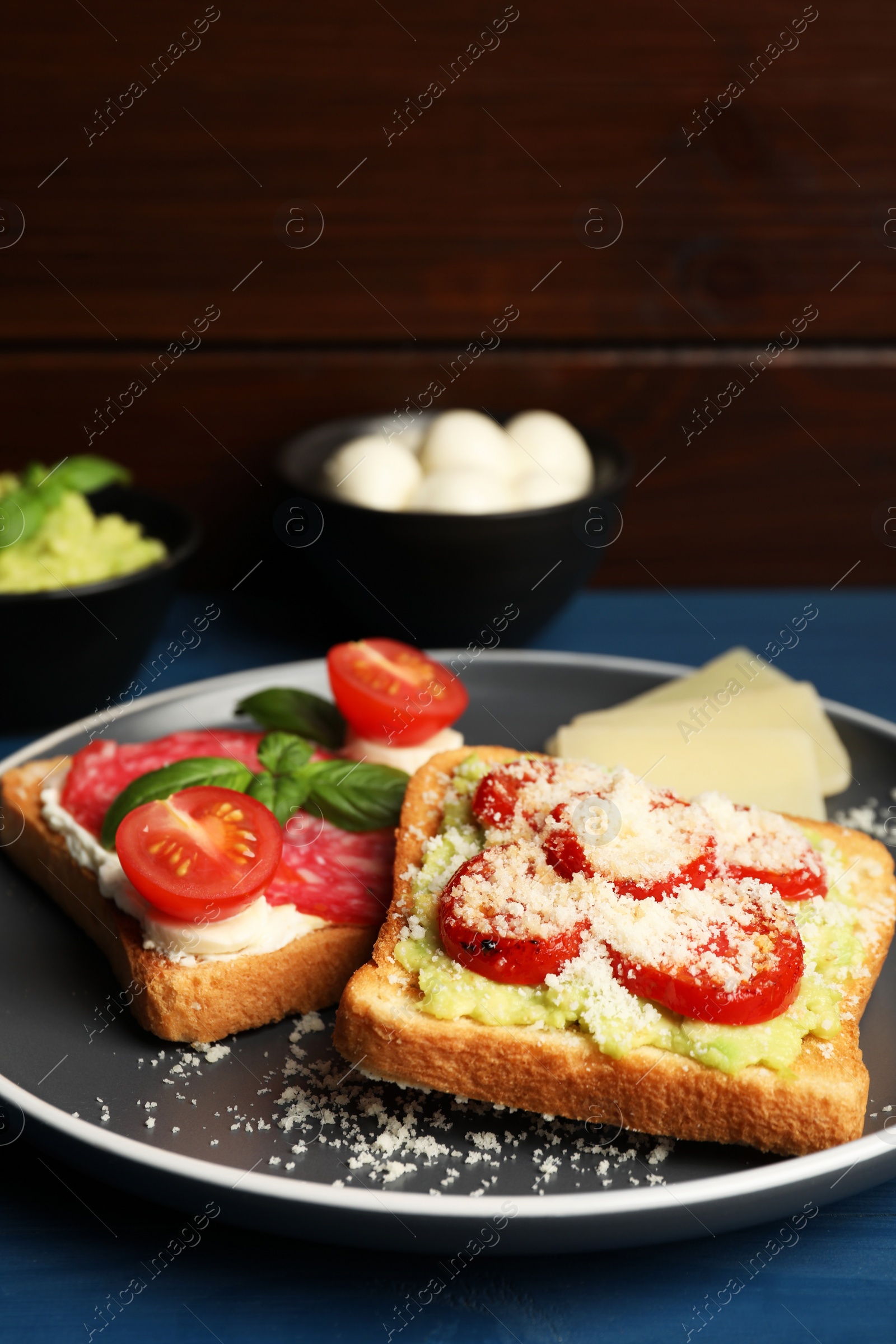 Photo of Tasty toasts with different toppings served on blue wooden table