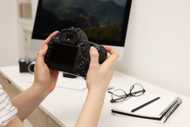 Photographer with camera at white table indoors, closeup