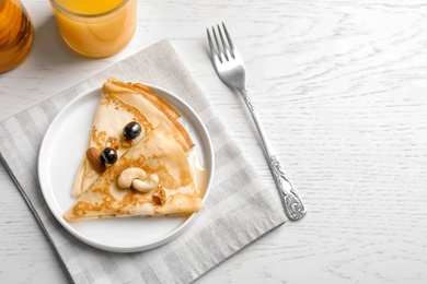 Photo of Thin pancakes with berries and nuts on plate, top view