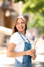 Photo of Young woman with cup of delicious milk shake outdoors