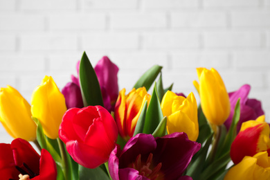 Photo of Beautiful spring tulips near white brick wall, closeup