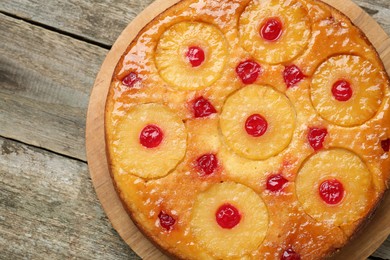 Photo of Tasty pineapple cake with cherries on wooden table, top view. Space for text