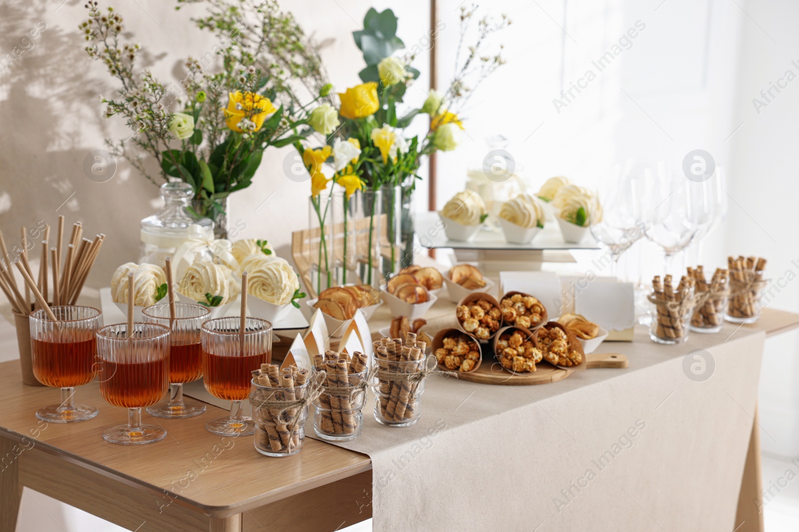 Photo of Delicious treats and glasses of drink on wooden table in room. Sweet buffet