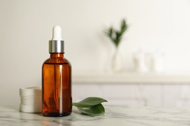 Photo of Cotton pads, leaves and makeup removal product on white marble table in bathroom. Space for text