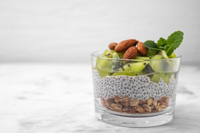 Photo of Delicious dessert with kiwi, chia seeds and almonds on white table, space for text