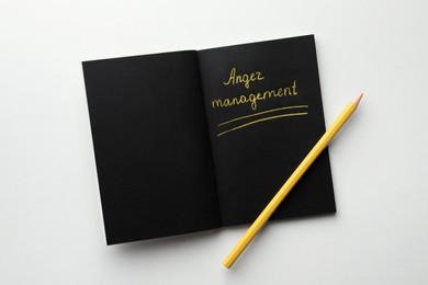 Photo of Black sketchbook with words Anger Management and pencil on white background, top view