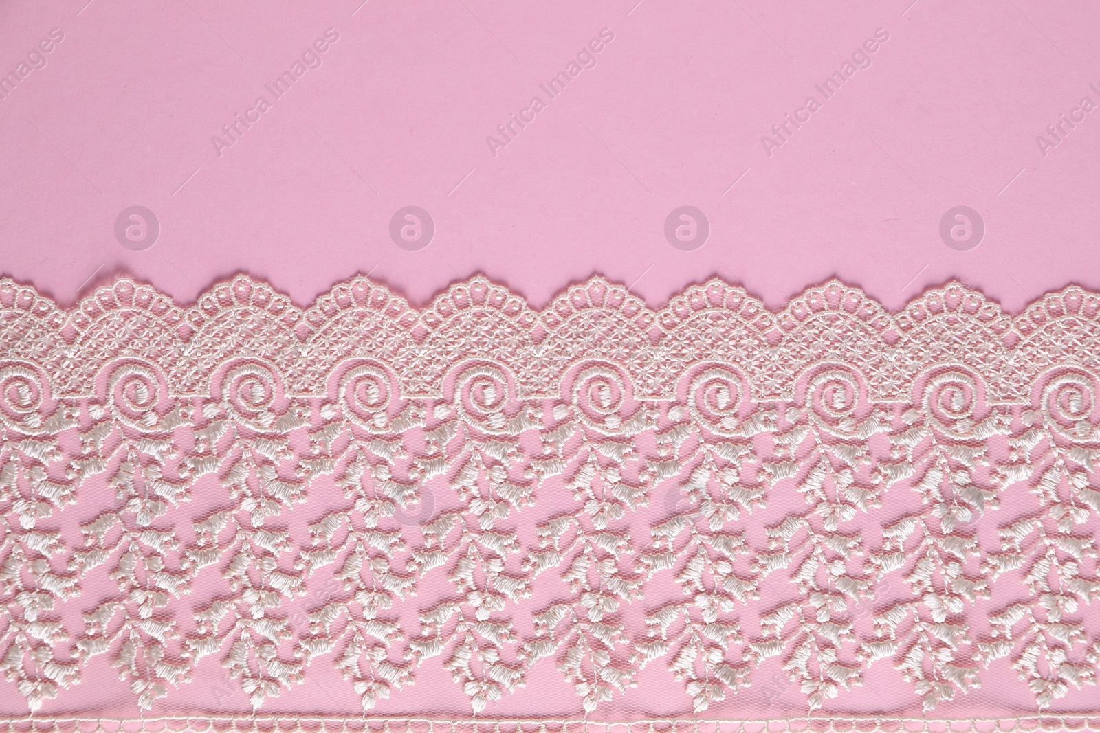 Photo of White lace on pink background, top view. Space for text