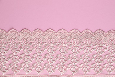 Photo of White lace on pink background, top view. Space for text