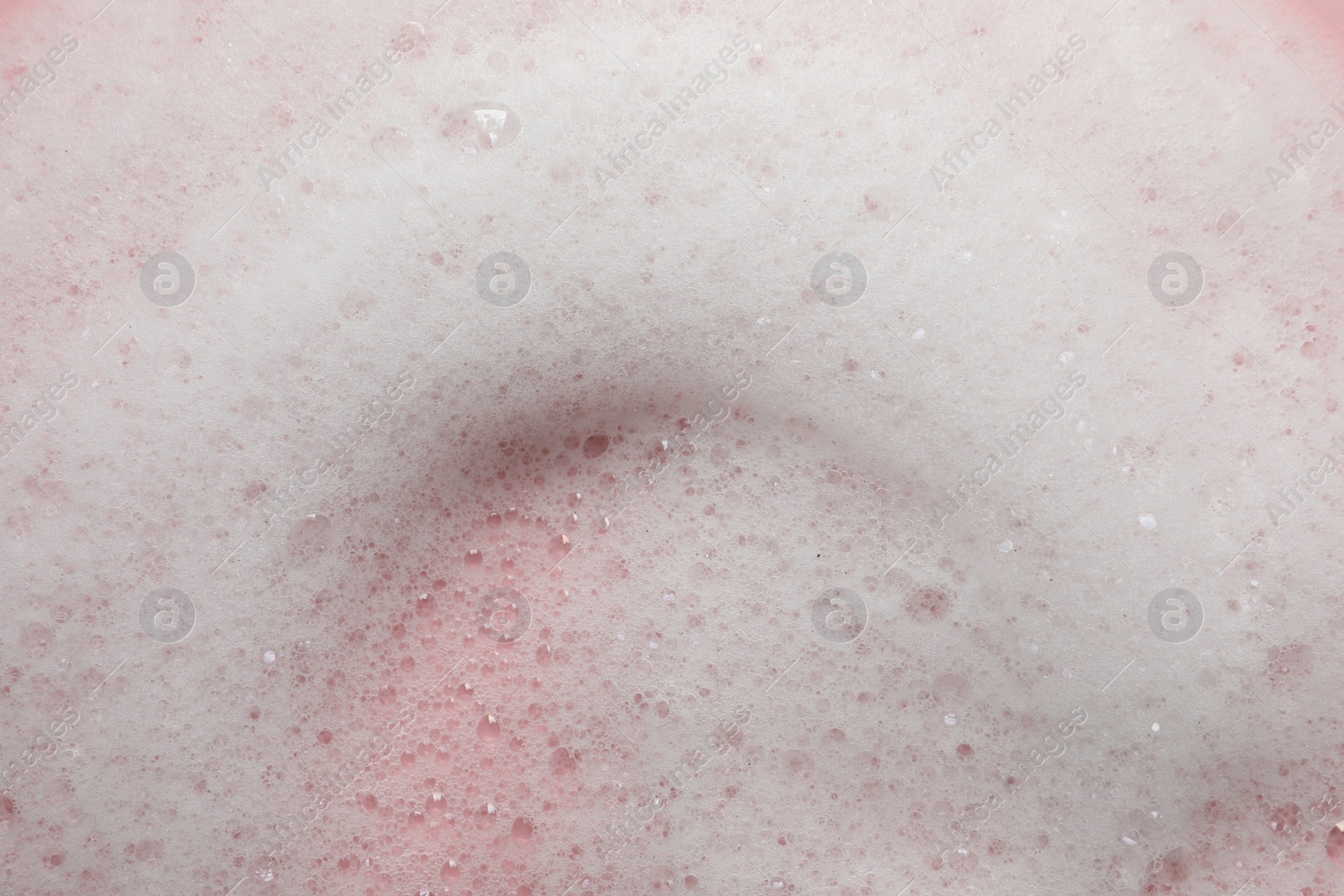 Photo of Fluffy soap foam on pink background, closeup