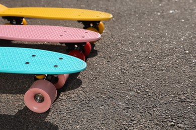 Photo of Different modern colorful skateboards on asphalt road  outdoors, closeup. Space for text