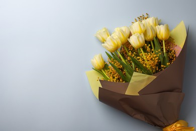Photo of Bouquet with beautiful tulips and mimosa flowers on light grey background, top view. Space for text