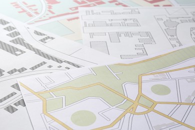 Photo of Many different cadastral maps of territory with buildings as background, closeup