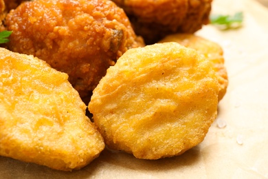Photo of Tasty fried chicken nuggets on parchment, closeup