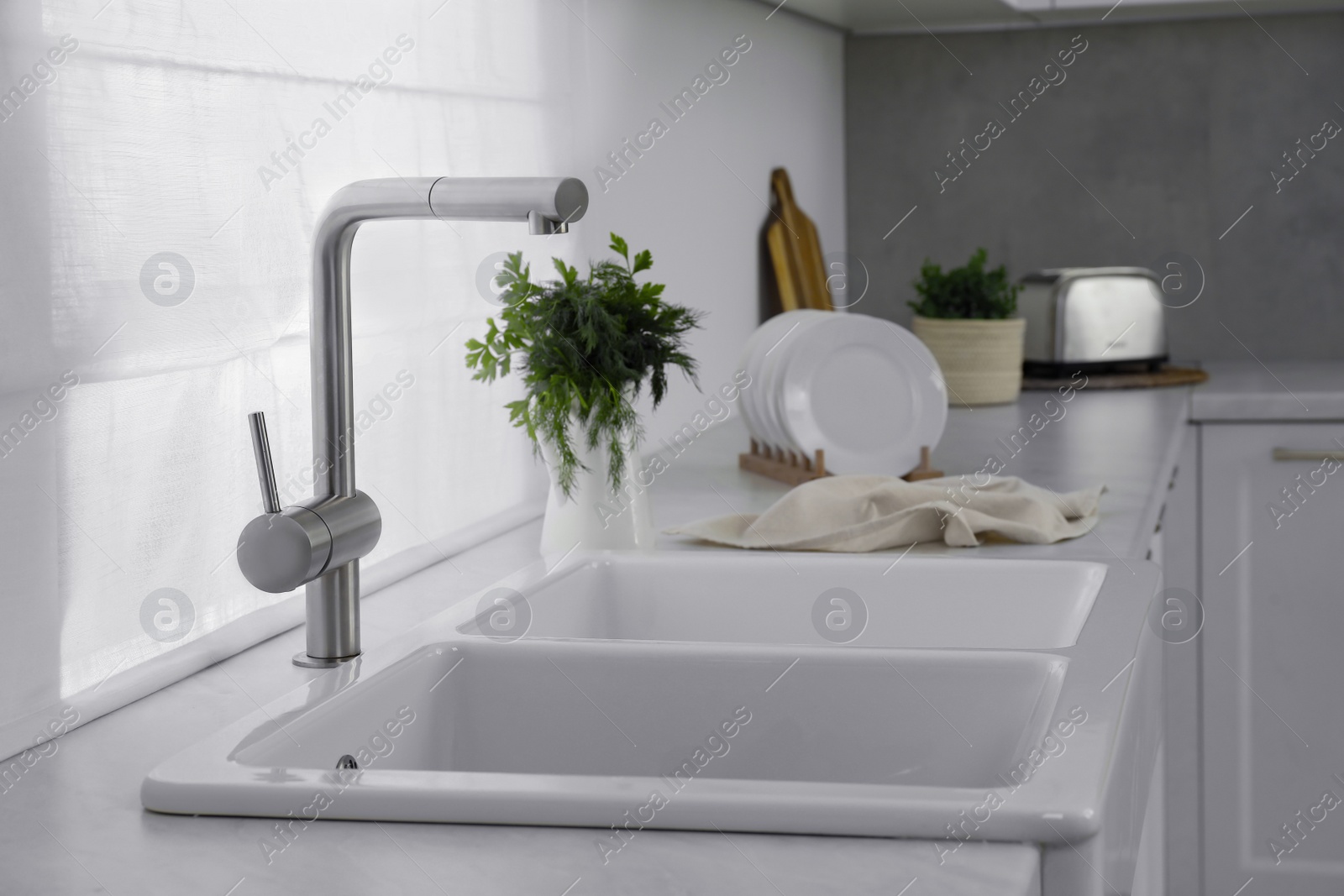 Photo of Modern sink and water tap on kitchen counter. Interior design