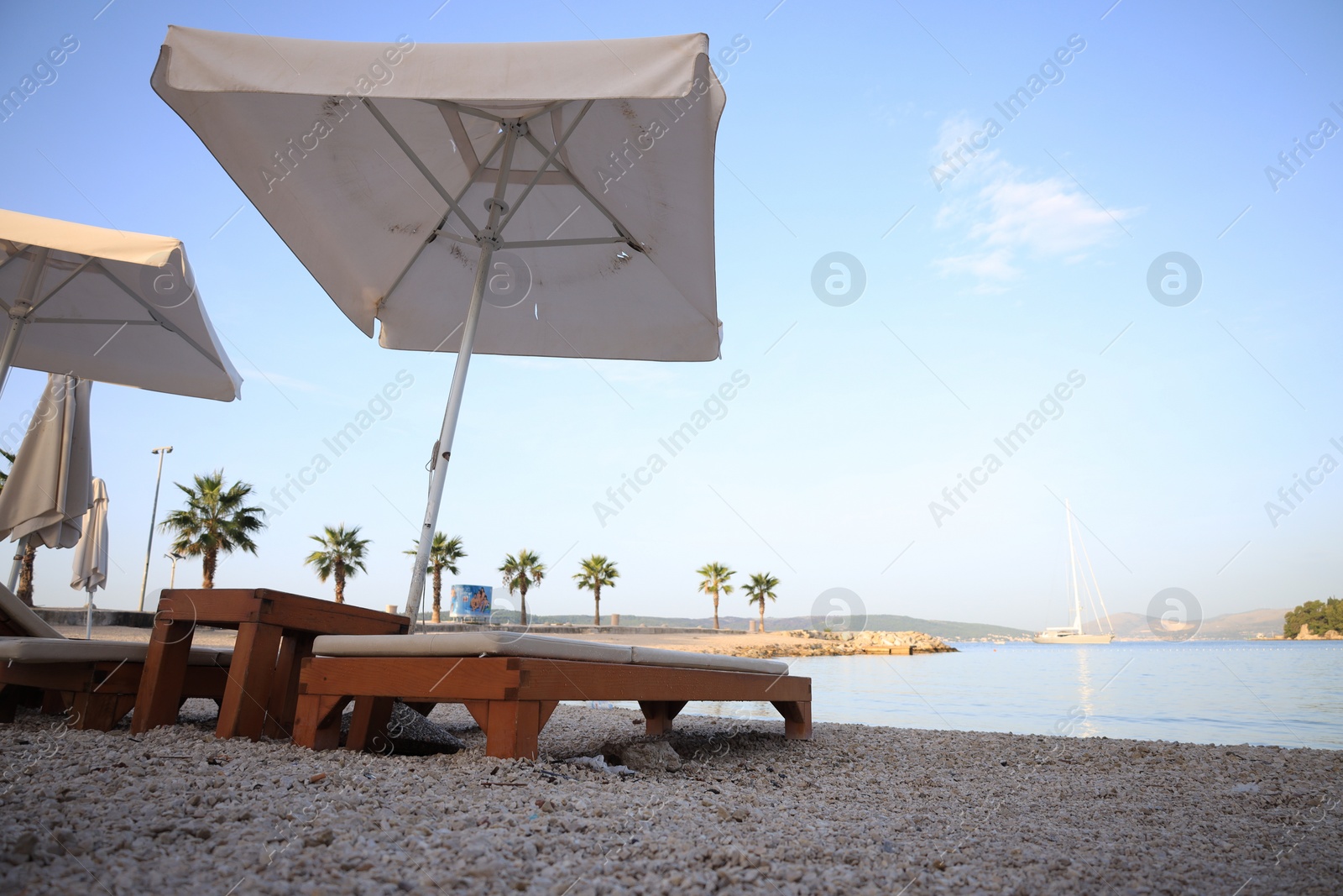 Photo of White beach umbrellas and sunbeds at resort, low angle view