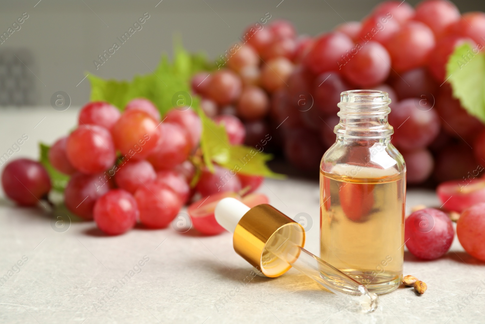 Photo of Natural grape seed oil and fresh berries on light table, space for text. Organic cosmetic