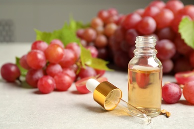 Photo of Natural grape seed oil and fresh berries on light table, space for text. Organic cosmetic