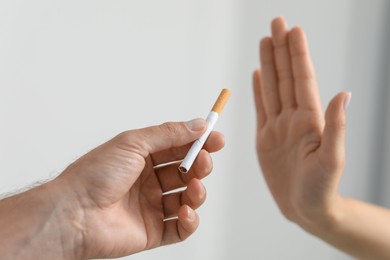 Photo of Stop smoking concept. Woman refusing cigarette on light background, closeup