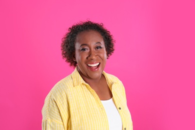 Portrait of happy African-American woman on pink background