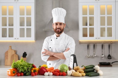 Photo of Portrait of happy professional chef near vegetables at marble table in kitchen