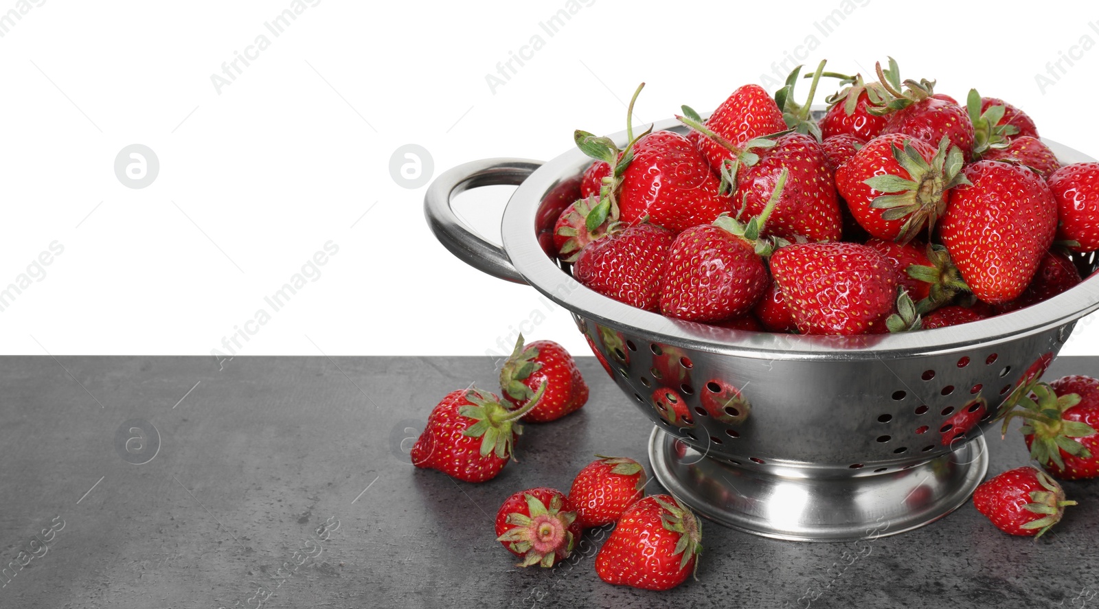 Photo of Metal colander with fresh strawberries on grey table against white background. Space for text