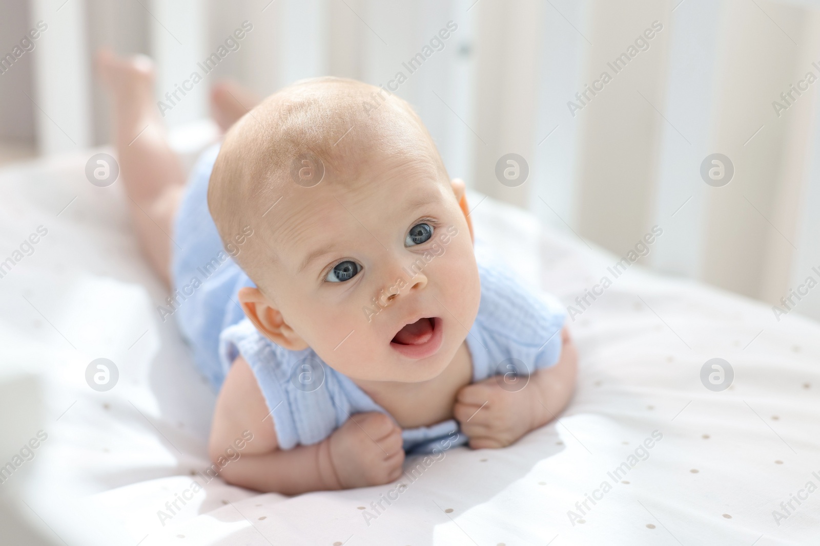 Photo of Cute little baby lying in crib at home, space for text