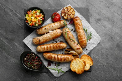 Photo of Tasty fresh grilled sausages with vegetables on grey table, flat lay