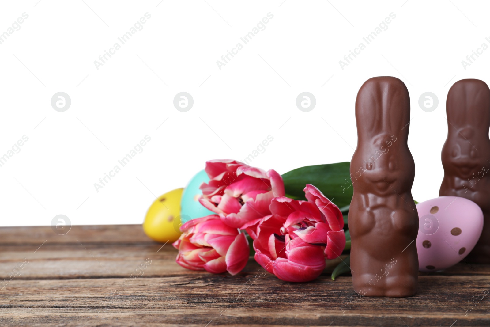 Photo of Chocolate Easter bunnies, eggs and tulips on wooden table against white background. Space for text