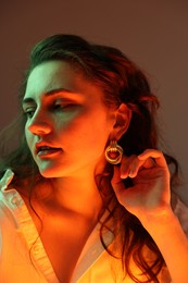 Portrait of beautiful young woman on color background with neon lights, closeup