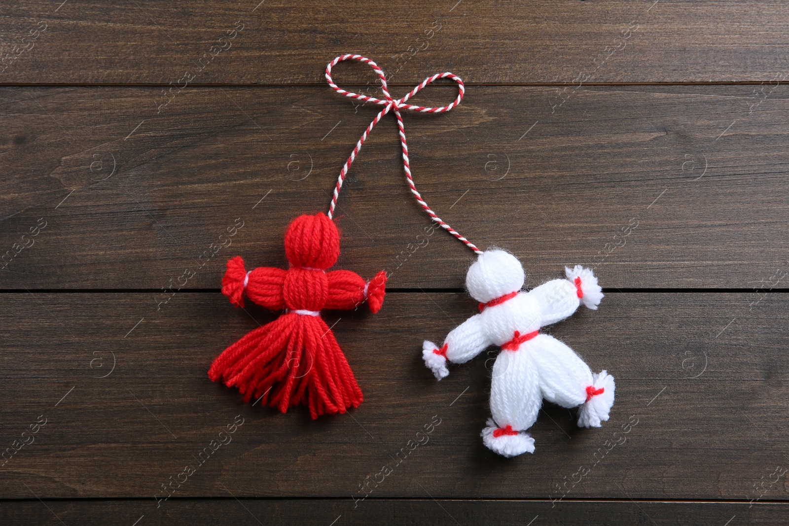 Photo of Traditional martisor shaped as man and woman on wooden background, top view. Beginning of spring celebration